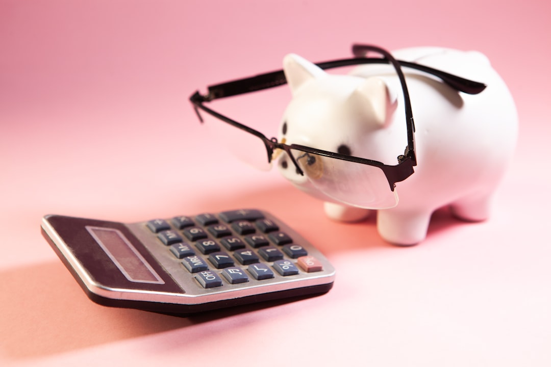 Piggy bank with eyeglasses and calculator on pink background